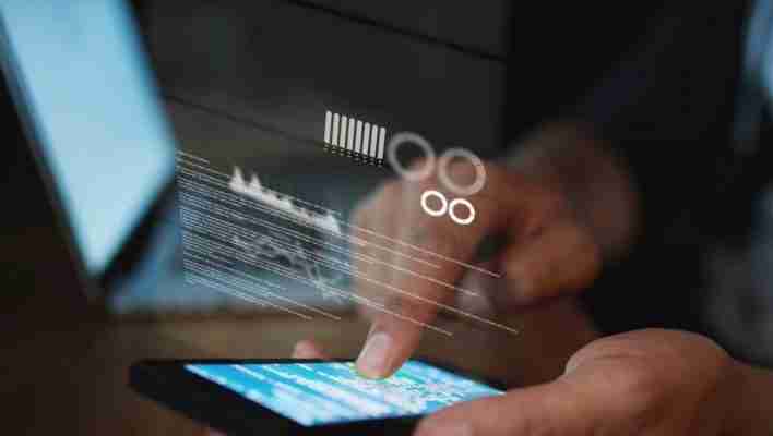 Individual interacting with a smartphone displaying digital data and graphics on the screen.