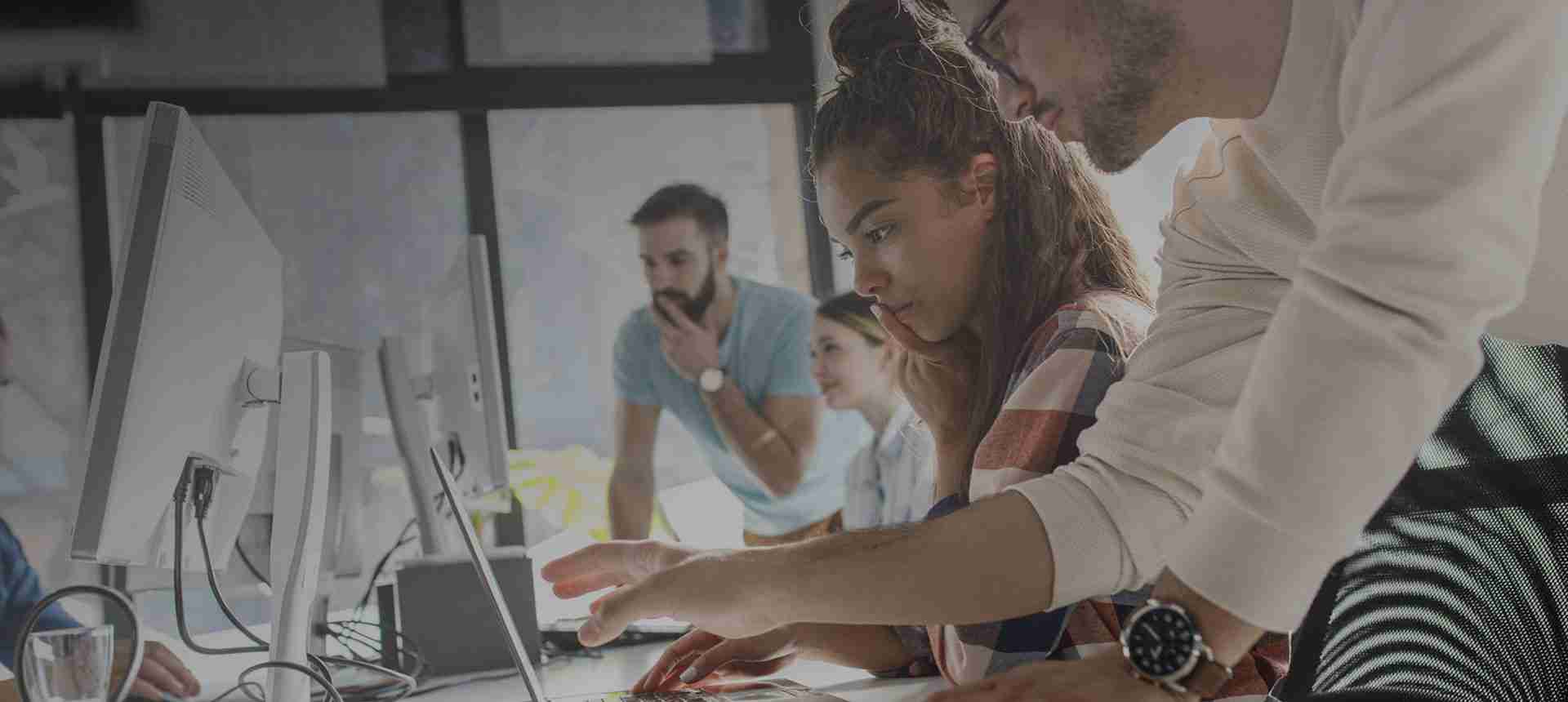 A group of individuals working together at computer workstations in an office setting.
